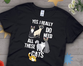 May include: Black t-shirt with a white graphic that says "Yes, I really do need all these cats". The graphic features five cats in different poses.