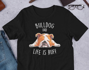 Puede incluir: Camiseta negra con un gráfico de bulldog blanco y el texto "Bulldog Dad Life is Ruff".