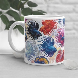 May include: White ceramic mug with a colorful pattern of betta fish. The fish are in shades of blue, red, orange, and purple.
