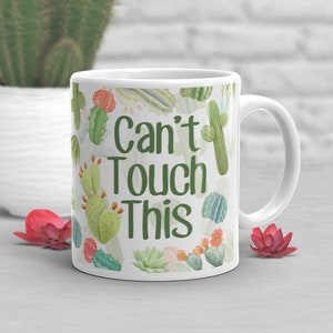 May include: White ceramic mug with a green cactus print and the text "Can't Touch This".