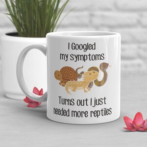 May include: White ceramic mug with a black graphic that says "I Googled my symptoms Turns out I just needed more reptiles". The graphic also includes a cartoon turtle, lizard, and snake.