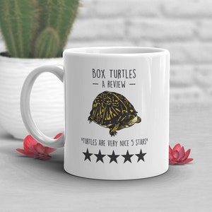 May include: White ceramic mug with a black and yellow illustration of a box turtle. The text "BOX TURTLES - A REVIEW -" is printed on the mug. Below the turtle is the text "TURTLES ARE VERY NICE 5 STARS" and five black stars.
