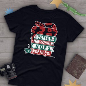 May include: Black t-shirt with a graphic of a red and black snake curled up on a stack of books. The books are labeled "Coffee", "Books", "Naps", and "Reptiles".