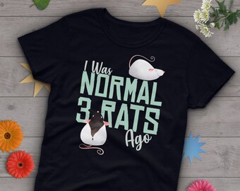 May include: Black t-shirt with a green graphic that says "I was normal 3 rats ago". The graphic also includes two cartoon rats, one white and one black.