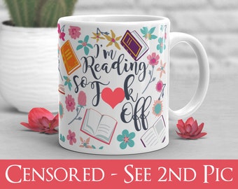 May include: White ceramic mug with a colorful design featuring books, flowers, and the text "I'm Reading So F*** Off". The text is in a black cursive font with a red heart in the middle of the word "F***".