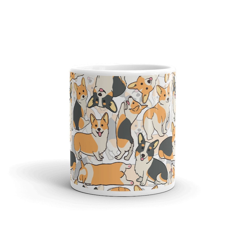 May include: White ceramic mug with a pattern of cartoon corgis in various poses. The corgis are black, white, and orange.