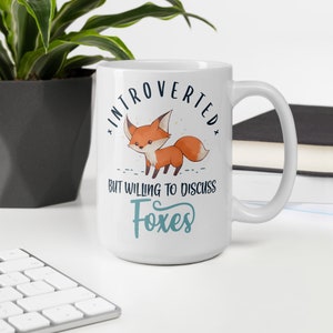 May include: White ceramic mug featuring a fox illustration and the text "Introverted but willing to discuss foxes".
