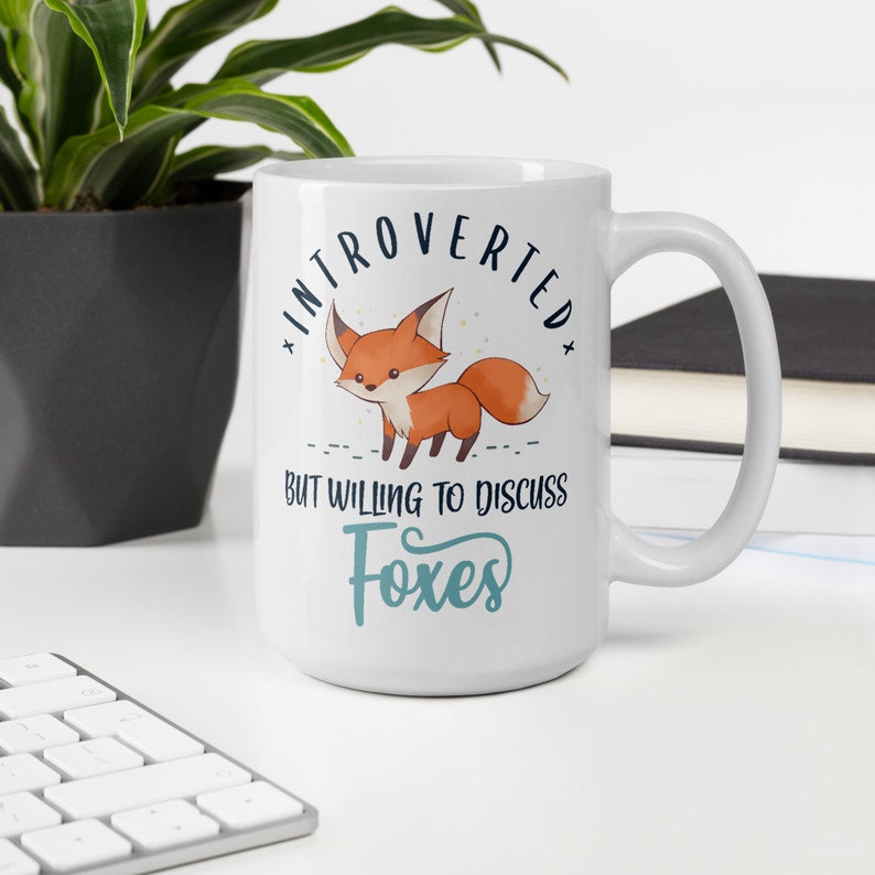 May include: White ceramic mug featuring a fox illustration and the text "Introverted but willing to discuss foxes".