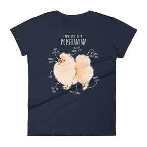 K&ouml;nnte beinhalten: Ein marineblaues Damen-T-Shirt mit einer wei&szlig;en Illustration eines Zwergspitz-Hundes. Die Illustration ist mit humorvollen anatomischen Merkmalen beschriftet, wie z. B. "Leckerli-Detektor", "Obsz&ouml;n flauschiger Bereich" und "Snack-Lagerung".