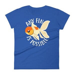 May include: A royal blue women's t-shirt with a white circle graphic featuring a cartoon goldfish and the text "Any Fin Is Possible".