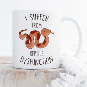 May include: White ceramic mug with a brown snake illustration and the text "I suffer from reptile dysfunction".