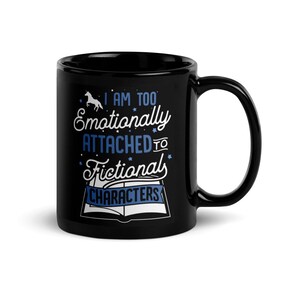 May include: Black coffee mug with a white design that says "I am too emotionally attached to fictional characters". The design includes a unicorn, stars, and an open book.