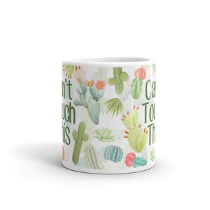 May include: White ceramic mug with a green, pink, and orange cactus print. The text "Can't Touch This" is printed on the mug.