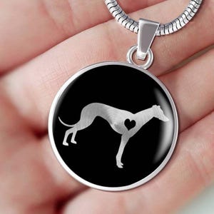 Peut inclure: Pendentif argenté représentant un lévrier avec un cœur sur fond noir. Le pendentif rond est suspendu à une chaîne argentée. Le lévrier est représenté de profil, avec un cœur sur la poitrine.