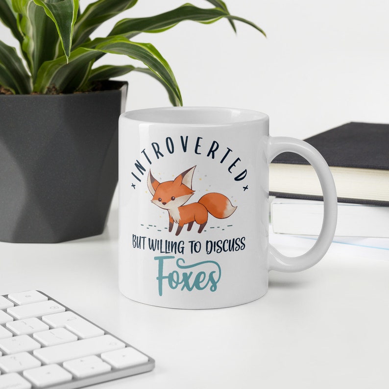 May include: White ceramic mug featuring a fox illustration and the text "Introverted but willing to discuss foxes".
