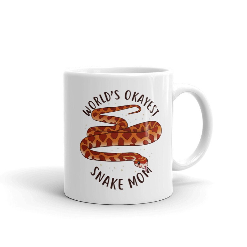 May include: White ceramic mug with a brown snake illustration and the text "World's Okayest Snake Mom".