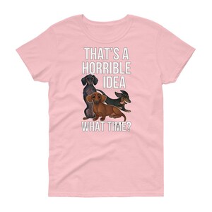 May include: Pink women's t-shirt with a graphic of three dachshunds and the text "That's a horrible idea. What time?"