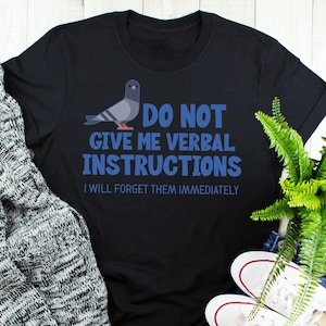 Puede incluir: Camiseta negra con un gráfico de paloma azul y el texto "No me dé instrucciones verbales Las olvidaré inmediatamente."