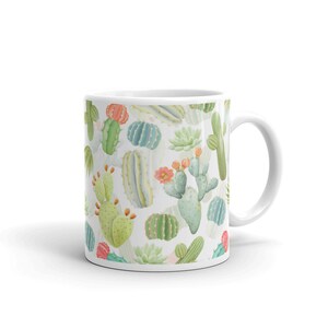 May include: White ceramic mug with a pattern of green, pink, and yellow cacti and succulents. The mug has a white handle.
