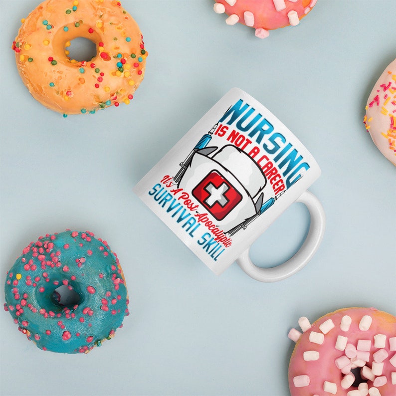 May include: White ceramic mug with a blue and red graphic of a nurse's hat and the text "Nursing is not a career, it's a post-apocalyptic survival skill!"