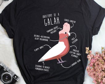 May include: Black t-shirt featuring a diagram of a Galah, a type of cockatoo, with labeled parts like "Flappy Arms" and "Magical Cotton Candy Plumage." The text "Anatomy of a Galah" is at the top. A fun, whimsical design.