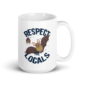 May include: White ceramic mug with a brown bat graphic and the text "Respect the Locals" in blue lettering.