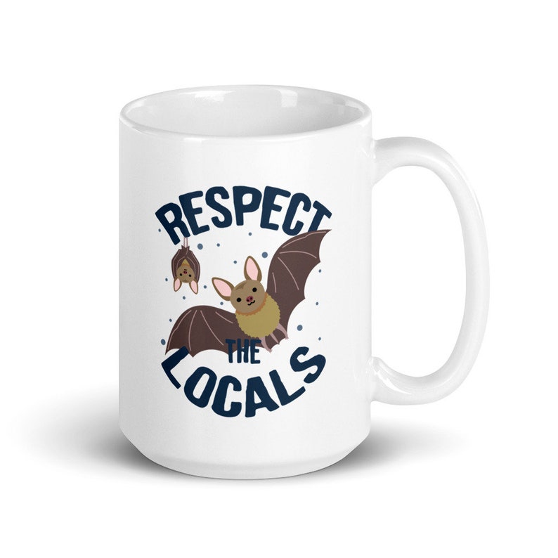 May include: White ceramic mug with a brown bat graphic and the text "Respect the Locals" in blue lettering.