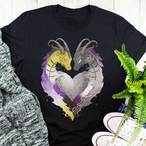 Puede incluir: Camiseta negra con un gráfico de dos dragones formando una forma de corazón con un esquema de color morado, blanco y amarillo. Los dragones se miran y sus colas están entrelazadas.