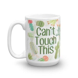 May include: White ceramic mug with a green and pink cactus print and the text "Can't Touch This" in green.