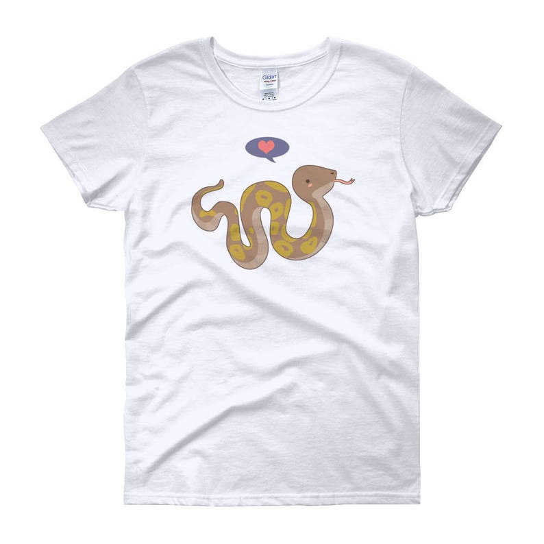May include: White women's t-shirt with a cartoon snake with yellow and brown markings. The snake is curled up and has a pink heart above its head. The text "Love" is in a blue speech bubble above the heart.