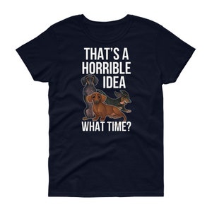 May include: Navy blue women's t-shirt with a white graphic of three dachshunds. The text "That's a horrible idea. What time?" is printed on the shirt.