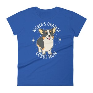 May include: A royal blue t-shirt with a white graphic of a cartoon corgi dog. The text "World's Okayest Corgi Mum" is printed around the dog.