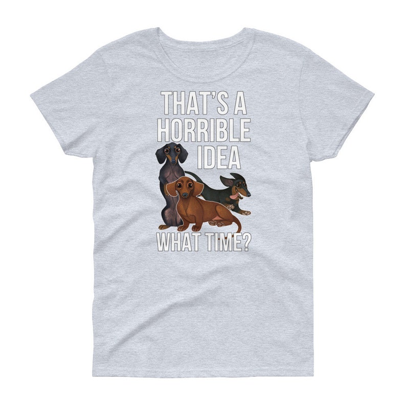 May include: A light gray t-shirt with a white graphic of three dachshund dogs. The text "That's a horrible idea. What time?" is printed on the shirt.
