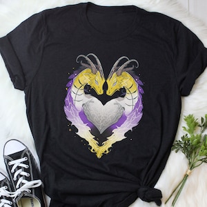 May include: Black t-shirt featuring a graphic of two yellow and purple dragons forming a heart shape. The dragons have a white heart in the centre of their intertwined bodies.