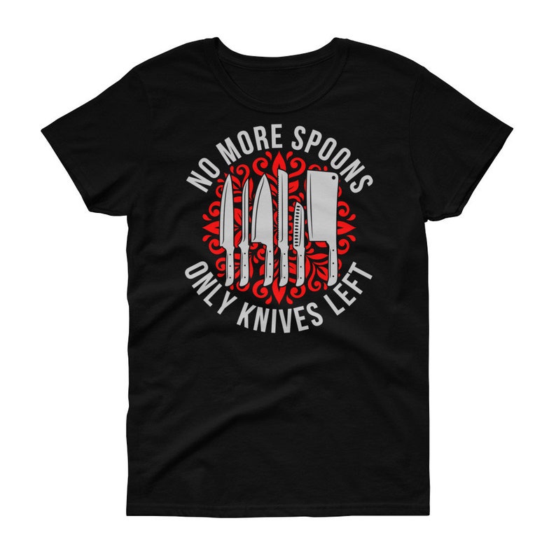 Puede incluir: Camiseta negra para mujer con un dise&ntilde;o gr&aacute;fico rojo y blanco. El gr&aacute;fico presenta un c&iacute;rculo con un patr&oacute;n floral rojo y un conjunto de cuchillos. El texto "No More Spoons Only Knives Left" est&aacute; escrito alrededor del c&iacute;rculo.