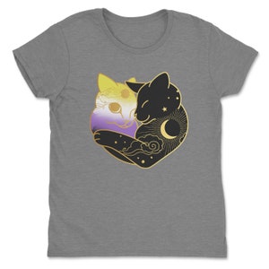 Op de afbeelding: Een grijs t-shirt met een afbeelding van twee omhelzende katten. E&eacute;n kat is gekleurd met de non-binaire pride vlag, de andere is zwart met een zon, maan en sterren ontwerp. De afbeelding is goudkleurig omlijnd.