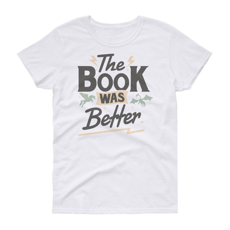 Pode incluir: Camiseta branca com um gr&aacute;fico preto que diz "The Book Was Better" com um unic&oacute;rnio e um drag&atilde;o de cada lado do texto.