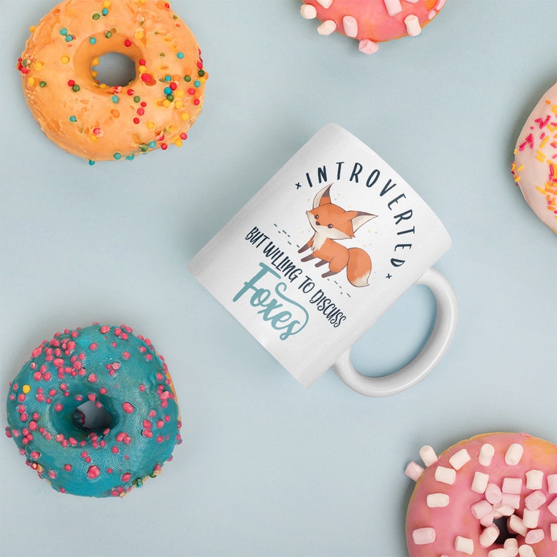 May include: White ceramic mug with a cartoon fox and the text "Introverted but willing to discuss foxes".
