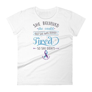 May include: White t-shirt with a blue and gray graphic that reads "SHE BELIEVED she could BUT SHE WAS REALLY Tired SO SHE DIDN'T" with a purple ribbon below the text that says "RHEUMATOID ARTHRITIS".