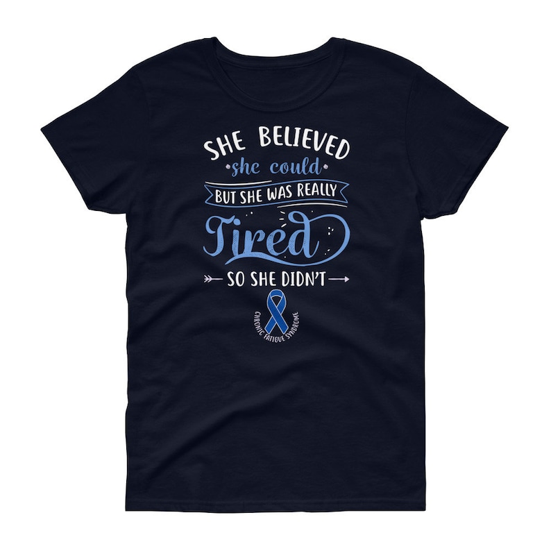 May include: Navy blue women's t-shirt with a white graphic that reads "She believed she could but she was really tired so she didn't."  The graphic also includes a blue ribbon with the text "Chronic Fatigue Syndrome".