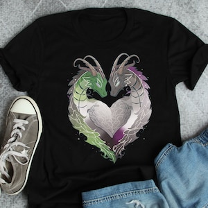 Puede incluir: Camiseta negra con un diseño de dragón verde y gris en forma de corazón. Los dragones se miran y tienen un corazón morado en el centro.