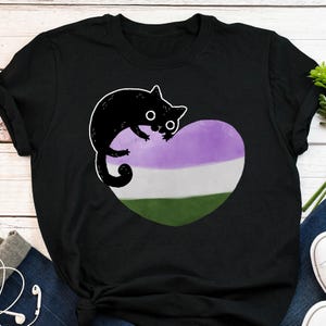 May include: Black t-shirt with a cartoon black cat design. The cat sits on a heart-shaped graphic in the non-binary flag colours: purple, white, and green. The cat has large eyes and a cute expression.