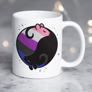 May include: White ceramic mug with a black and white yin yang symbol featuring a pink, purple, black, and blue color scheme. The symbol is surrounded by small white stars.