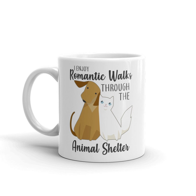 May include: White ceramic mug with a brown dog and white cat illustration. The text reads "I enjoy Romantic Walks through the Animal Shelter".