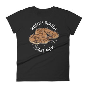 May include: Black women's t-shirt with white text that reads "World's Okayest Snake Mom" and a cartoon image of a brown and tan snake.