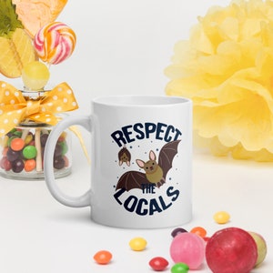 May include: White ceramic mug with a blue and white graphic that says "Respect the Locals" with a cartoon bat illustration.