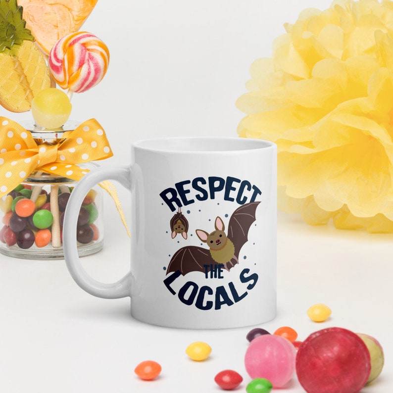 May include: White ceramic mug with a blue and white graphic that says "Respect the Locals" with a cartoon bat illustration.