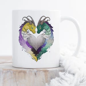 May include: A white ceramic mug featuring a graphic illustration of two dragons facing each other, their bodies forming a heart shape. The left dragon is yellow and purple, while the right dragon is green and blue, both with intricate scale details.