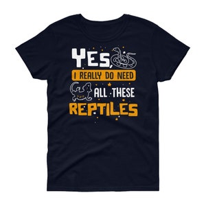 May include: A navy blue t-shirt with a white graphic of a snake and a lizard. The text on the shirt reads "Yes, I really do need all these reptiles".