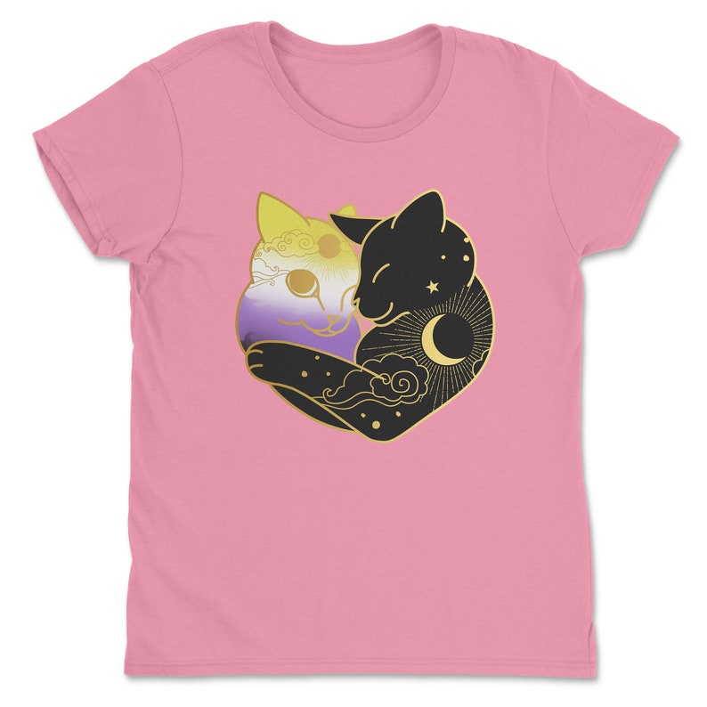 Op de afbeelding: Roze t-shirt met een afbeelding van twee omhelzende katten. E&eacute;n kat is gekleurd met de non-binaire pride-vlag, de andere is zwart met een zon-, maan- en sterrenontwerp. De katten omarmen elkaar.